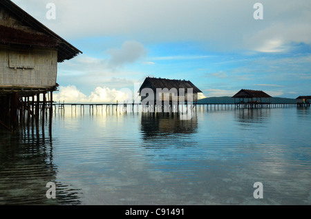 Cases traditionnelles sur les récifs coralliens à Kri Eco Resort, Raja Ampat îles de Papouasie occidentale dans l'océan Pacifique, l'Indonésie. Banque D'Images