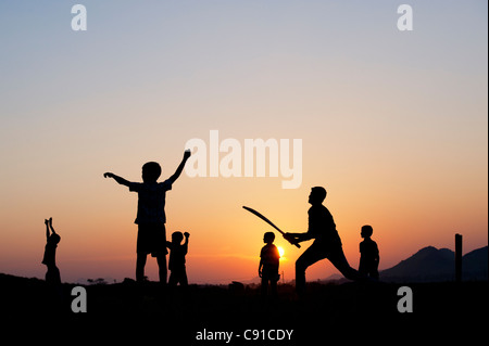 Silhouette de jeunes garçons à jouer au cricket indien contre un fond coucher de soleil Banque D'Images