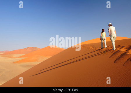 Deux femmes marchant sur des dunes de sable rouge de Sossusvlei Sossusvlei dunes 45 Parc National Namib Naukluft Namib Namibie Namib desert Banque D'Images