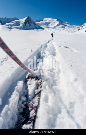 Low angle view of skieurs cordée de quitter le camp sur le glacier du triumvirat à escalader le mont Amaranta, montagnes Tordrillo, Alaska Banque D'Images