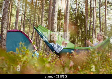 Women relaxing in hammock at campsite Banque D'Images