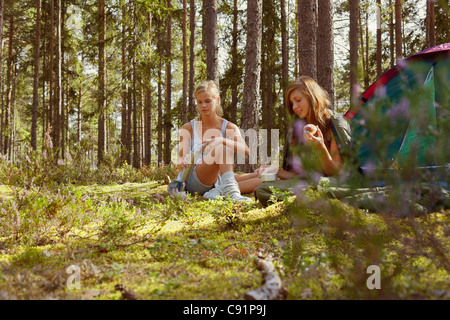 Les femmes assises de camping en forêt Banque D'Images