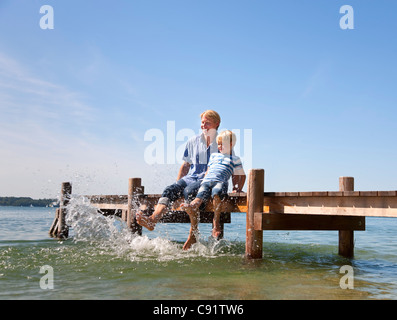 Père et fils pieds ballants dans le lac Banque D'Images