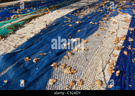 Bleu vert et blanc des filets des pêcheurs avec corde à sécher sur le côté du port avec les feuilles d'automne tombées sur le dessus Banque D'Images