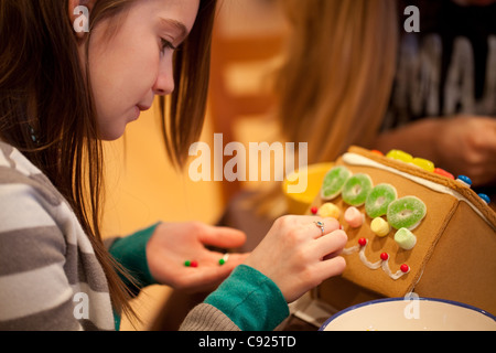 Fille préadolescente décore a gingerbread house Banque D'Images