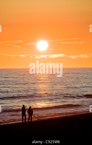 Un couple marche le Homer Spit plage au coucher du soleil le long de la baie Kachemak, péninsule de Kenai, Southcentral Alaska, l'été Banque D'Images