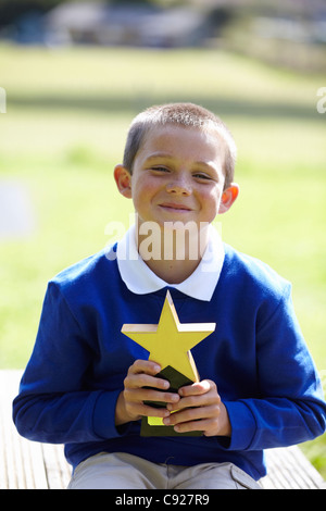 Smiling boy holding trophy en plein air Banque D'Images