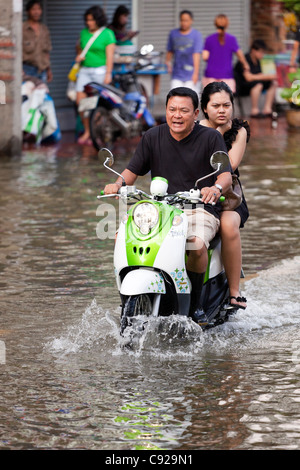 Couple riding moto à travers l'eau d'inondation en centre-ville de Bangkok, Thaïlande Banque D'Images