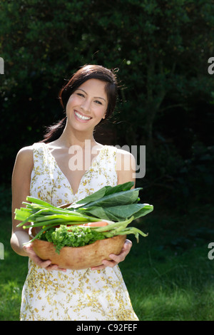 Femme transportant brassée de légumes Banque D'Images