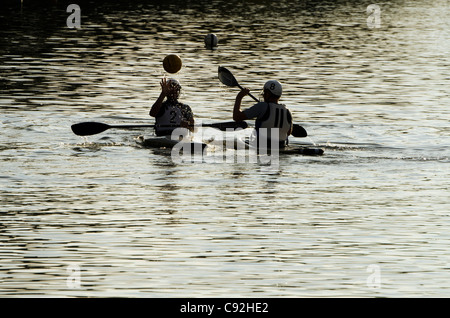 Une silhouette de deux jeunes hommes jouant canoe water-polo sur Bury Lake Rickmansworth Aquadrome Herts UK Banque D'Images