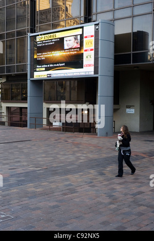 Femme marchant sur place portsmouth guildhall géant écran de télévision publique qui passe Banque D'Images