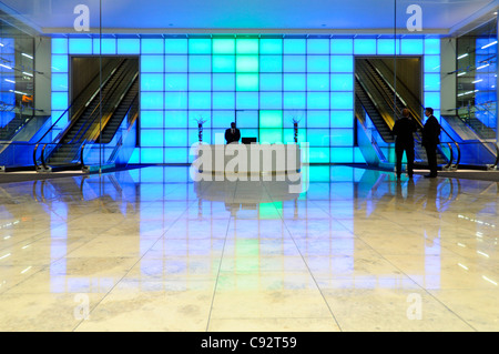 Mur lumineux bleu coloré variable derrière le comptoir de réception dans le hall d'entrée de l'immeuble de bureaux avec escaliers roulants dans la ville de Londres Angleterre Royaume-Uni Banque D'Images