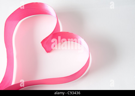 Forme de coeur composé de ruban rose sur fond blanc Banque D'Images