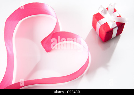 Forme de coeur composé de ruban rose, avec petit coffret à proximité Banque D'Images