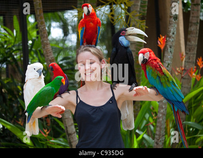 Bali, Ubud. Un touriste pose avec un assortiment d'oiseaux à Bali Bird Park. M. Banque D'Images