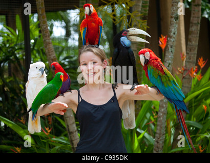 Bali, Ubud. Un touriste pose avec un assortiment d'oiseaux à Bali Bird Park. M. Banque D'Images