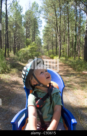 Un petit garçon aime le paysage de sa bicyclette siège enfant comme sa maman passe par la forêt des Landes dans le sud ouest de la France Banque D'Images