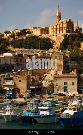 Gozo, Malte, Europe ; Mgarr Harbour avec des bateaux de pêche traditionnels et une église néo-gothique dominant le paysage urbain Banque D'Images