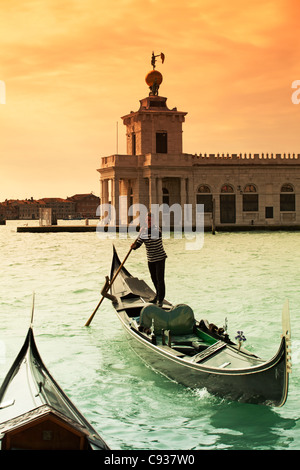 Venise, Vénétie, Italie ; une gondole gondolier son aviron sur le Grand Canal en face de la Dogana récemment restauré Banque D'Images