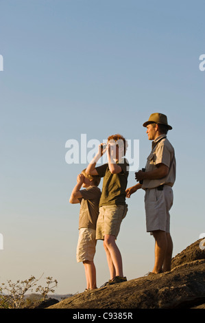 Au Malawi, la Réserve de faune majete. Un guide avec Robin Pope Safaris prend les enfants sur une famille safari sur un buisson à pied. Banque D'Images