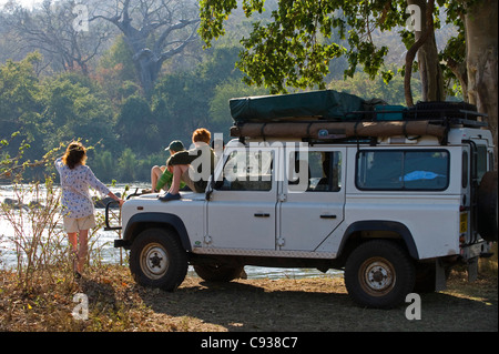 Au Malawi, la Réserve de faune majete. Sur la famille safari donnent sur la Shire River à partir de leur véhicule de safari. M. Banque D'Images