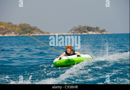 Au Malawi, le lac Malawi National Park. Jeune garçon se déplace sur un anneau gonflable tiré par un hors-bord.(MR) Banque D'Images