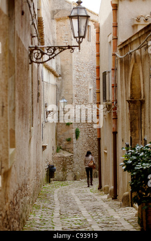Sicile, Italie, Europe de l'Ouest ; une femme marche à travers les rues étroites d'Erice Banque D'Images