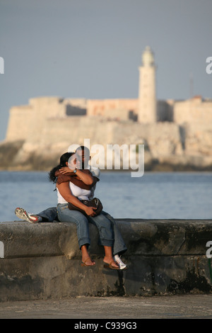 Couple aimant à le Malecon de La Havane, Cuba. Le Château del Morro vu dans l'arrière-plan. Banque D'Images