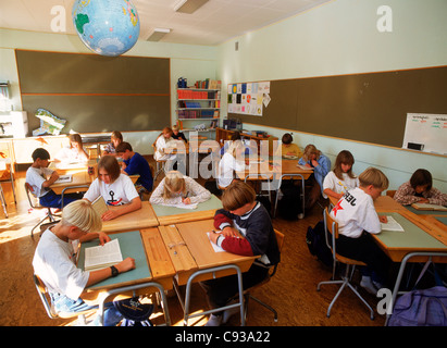 Les enfants de l'école élémentaire la lecture et l'écriture à un bureau en classe sous globe en Suède Banque D'Images