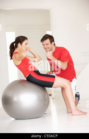 Femme avec un entraîneur personnel dans la salle de gym à domicile Banque D'Images