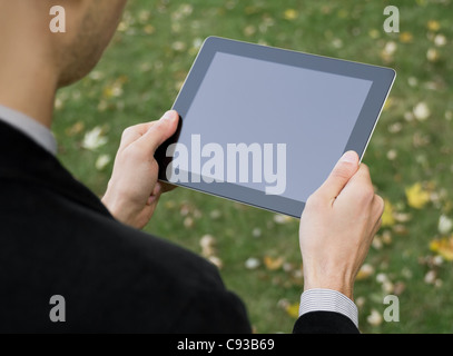 Businessman in a park holding a blank tablet PC écran tactile. Banque D'Images