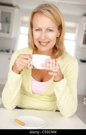 Femme d'âge moyen avec du café à la maison Banque D'Images