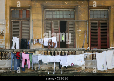 L'homme fume cubain au balcon dans le centre historique de La Havane, Cuba. Banque D'Images