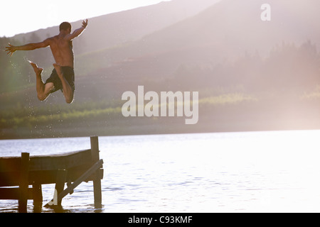 Jeune homme de sauter dans le lac Banque D'Images