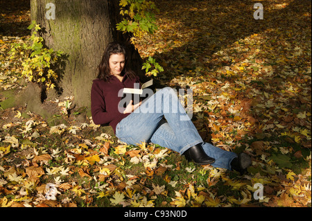 Femme lisant un livre en scène d'automne Banque D'Images