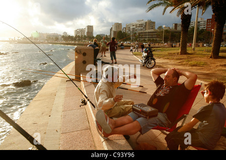 Les gens la pêche et la marche à pied le long de la Rambla, le Riverfront Promenade, Montevideo, Uruguay. Banque D'Images