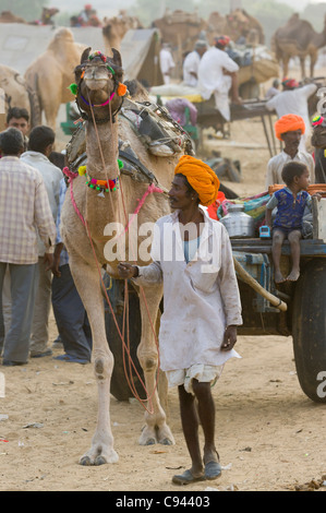 L'homme du Rajasthan dans un turban orange à la tête d'un panier de chameau, Puhkar Mela, Pushkar, Rajasthan, India Banque D'Images