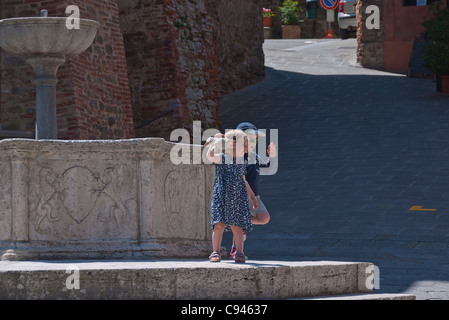 Deux jeunes enfants, un garçon et une fille, posent pour une photo de la ville fontaine en Panicale, Italie Banque D'Images