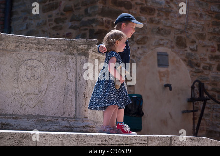 Deux très jeunes enfants italiens s'en tenir à une fontaine avec la jeune fille tenant son animal en peluche se préparant à se faire prendre en photo. Banque D'Images