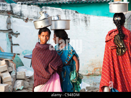 Trois castes inférieures adolescentes indiennes transportant des pots de riz sur la tête. L'Andhra Pradesh, Inde Banque D'Images