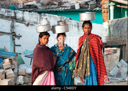 Trois castes inférieures adolescentes indiennes transportant des pots de riz sur la tête. L'Andhra Pradesh, Inde Banque D'Images