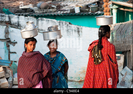 Trois castes inférieures adolescentes indiennes transportant des pots de riz sur la tête. L'Andhra Pradesh, Inde Banque D'Images