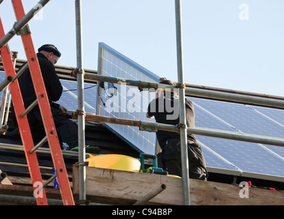 Montage des ouvriers nouveaux panneaux solaires à un toit de maison pour le système de tarifs de rachat. Pays de Galles, Royaume-Uni, Angleterre Banque D'Images