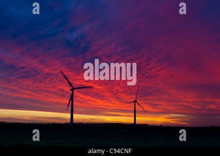 2 éoliennes, une couverture et un champ, silhouetté contre un mauvais/sunrise glorieux Banque D'Images