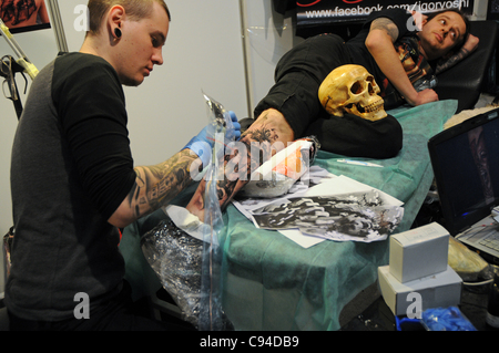 12.11.2011 Varsovie, Pologne. Homme obtient un nouveau tatouage sur la jambe au cours de la première journée de tattoo, body painting et pierceing show - Body Art 'Convention' dans un palais de la Culture et de la science à Varsovie. Banque D'Images