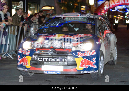 Sebastien Loeb (France) et Daniel Elena (Monaco) dans leur Citroën Total WRT Citroën DS3 WRC à faire leur chemin à travers le centre de Cardiiff ce soir au jour 3 de la FIA WRC Wales Rally GB. Banque D'Images