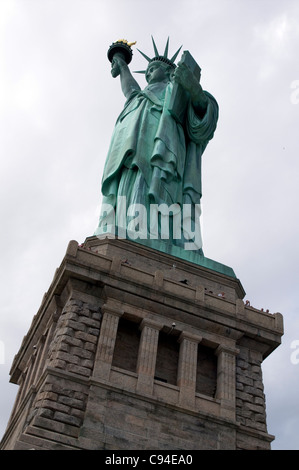 Statue de la liberté avec de minuscules têtes des personnes à la recherche sur le socle ledge Banque D'Images