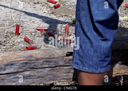 Des cartouches ont été utilisées lors d'un tir de pigeon d'argile et de l'ombre d'un homme qui tiraient un fusil de chasse Banque D'Images