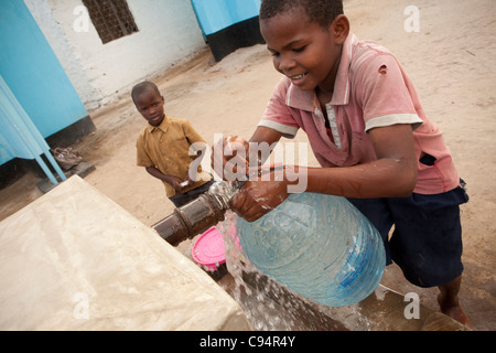 Un garçon va chercher de l'eau à un puits à Dar es Salaam, Tanzanie, Afrique de l'Est. Banque D'Images