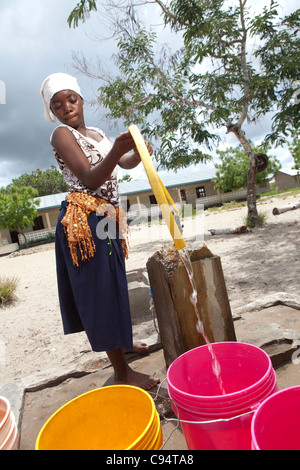 Une jeune femme se remplit des seaux d'eau à une communauté bien à l'extérieur de Dar es Salaam, Tanzanie, Afrique de l'Est. Banque D'Images